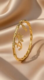 This is a gold-plated nautical-themed bamboo bangle bracelet,