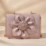 faux leather crossbody bag with a 3D flower design and a golden chain strap.